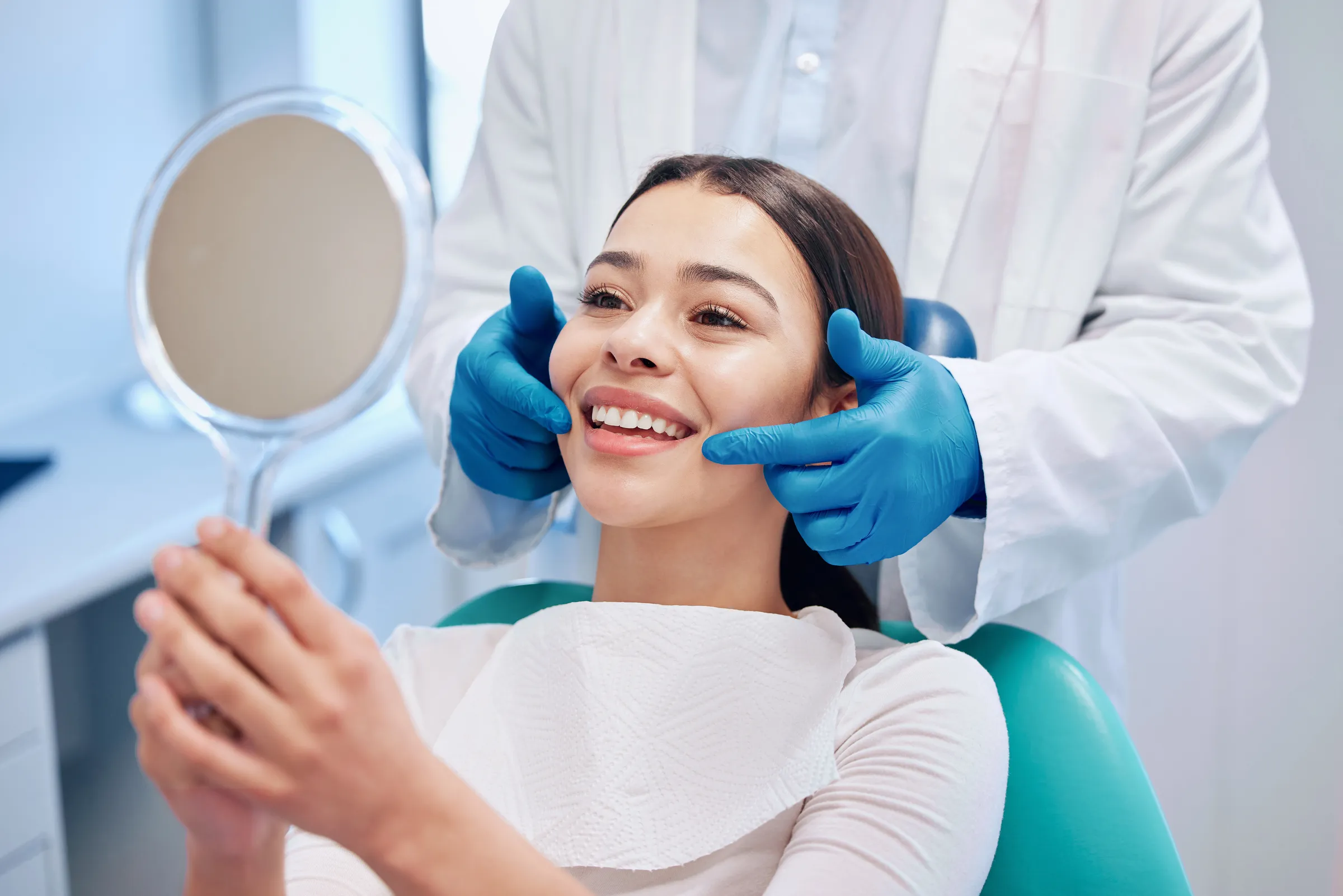 Patient admiring her smile in a hand mirror after a cleaning