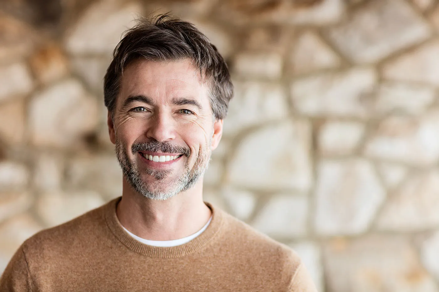 Smiling middle-aged man in front of a stone wall