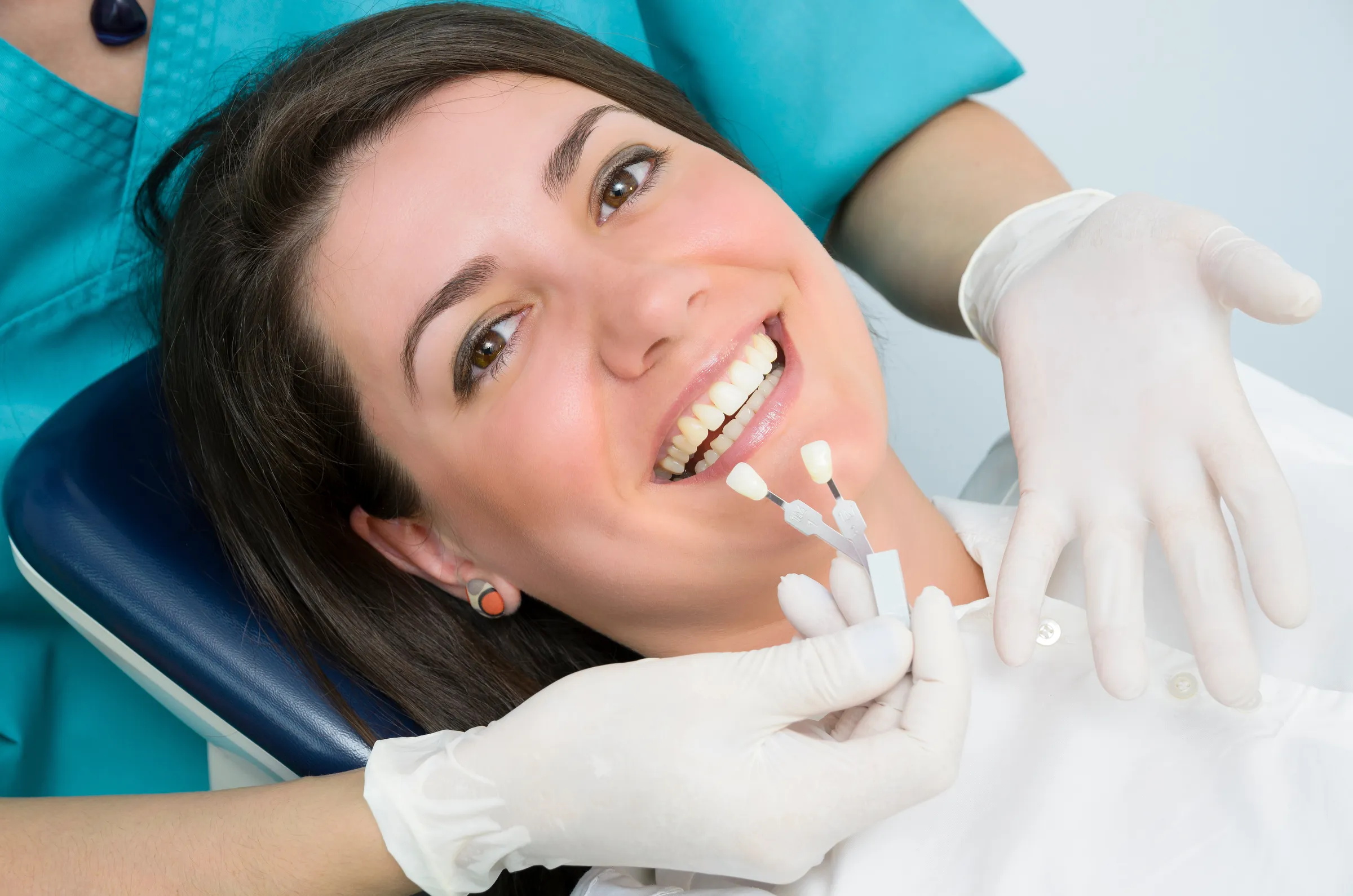 Patient smiling as the dentist holds a shade guide to her teeth