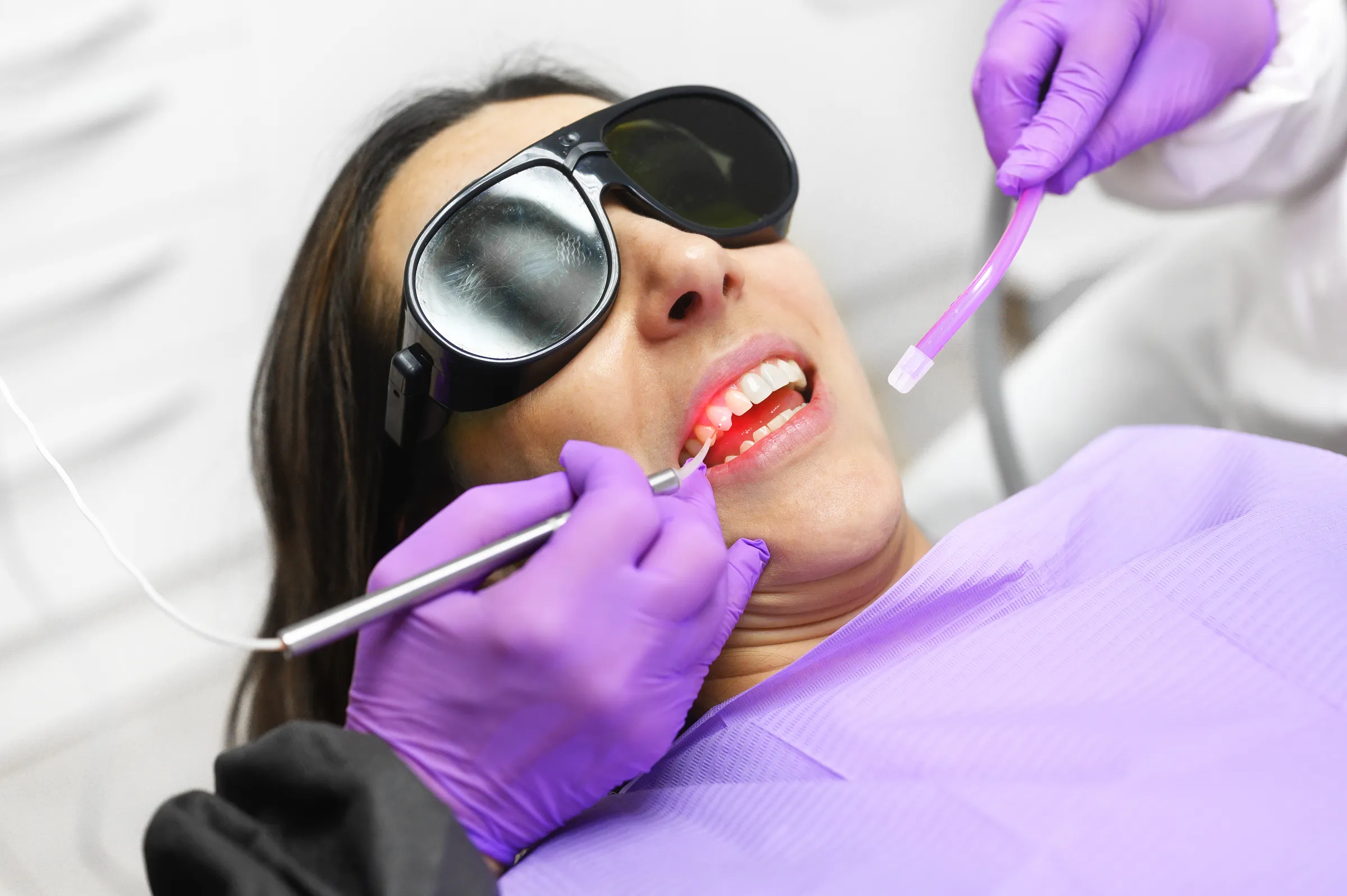Patient in protective glasses receiving laser gum treatment