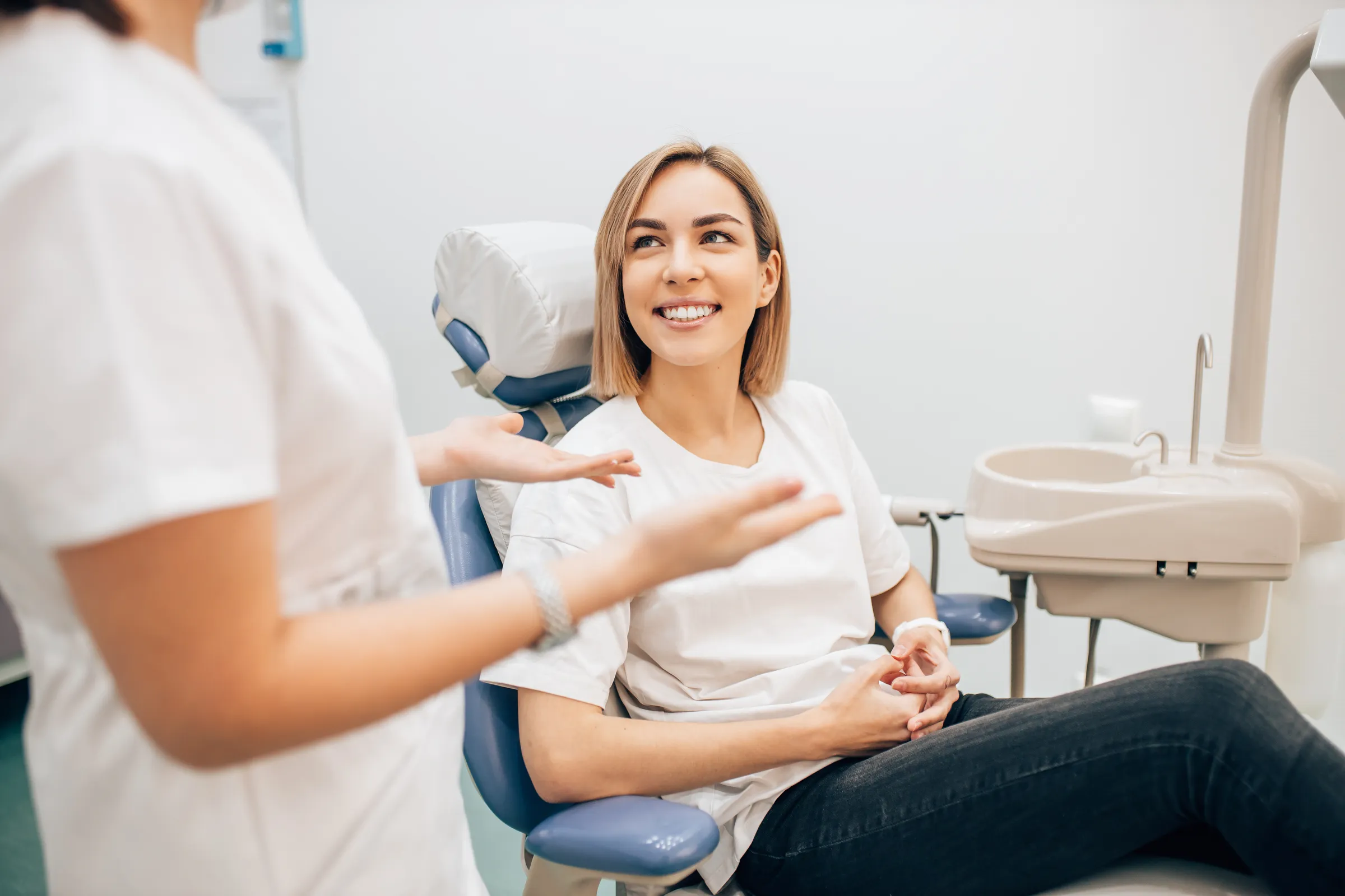 Smiling woman in a dental chair talking with her dentist